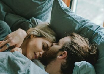 man kissing woman's forehead while lying on bed