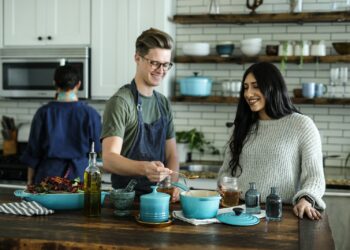 smiling man standing and mixing near woman in kitchen area of the house